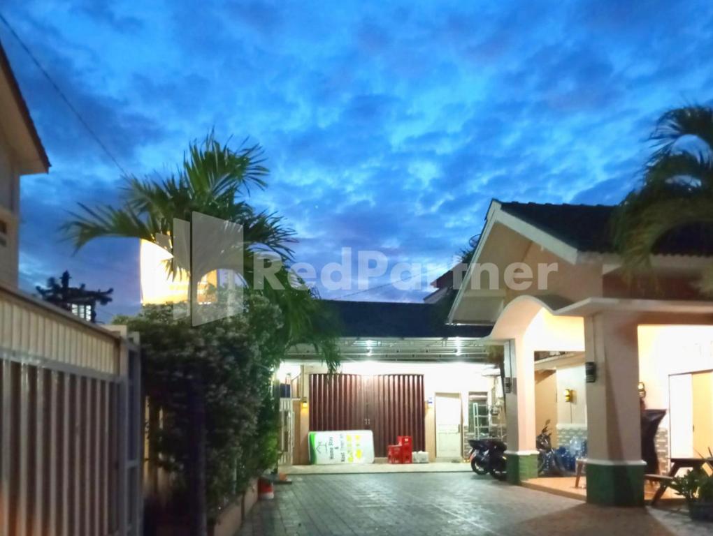 a house with a palm tree in front of it at Isa Homestay Kudus Mitra Reddoorz in Kudus