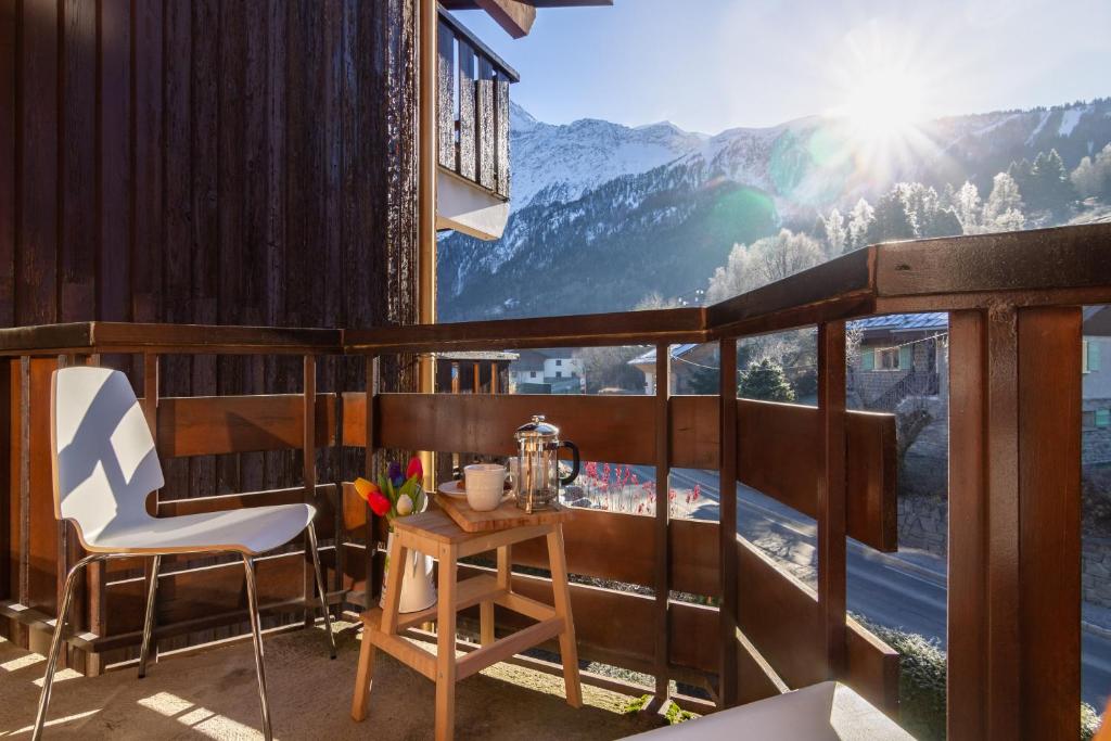 balcón con mesa, sillas y vistas a la montaña en Résidence Le Prarion 24A ski in- ski out - Happy Rentals, en Les Houches