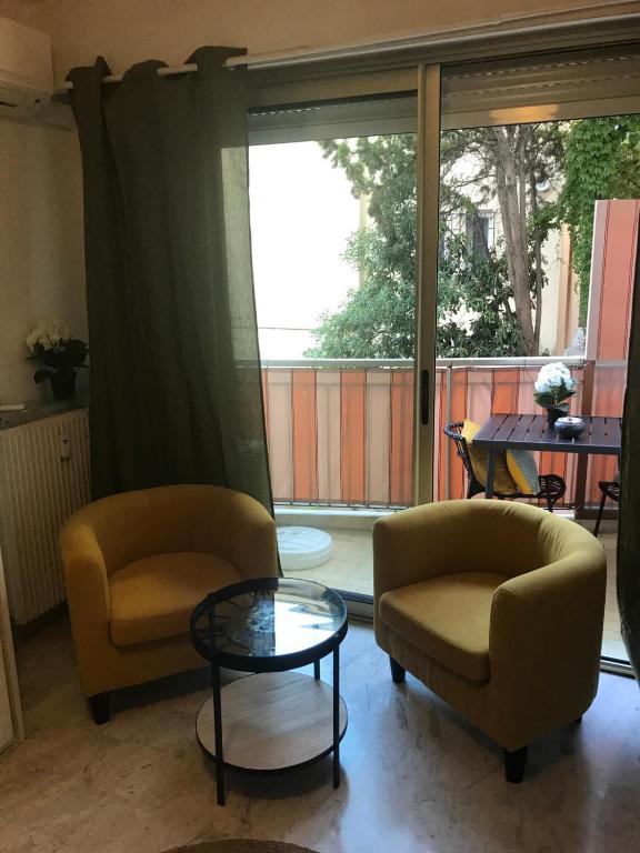 - un salon avec deux chaises et une table en verre dans l'établissement Charmant Studio proche du Centre-Ville, à Nice