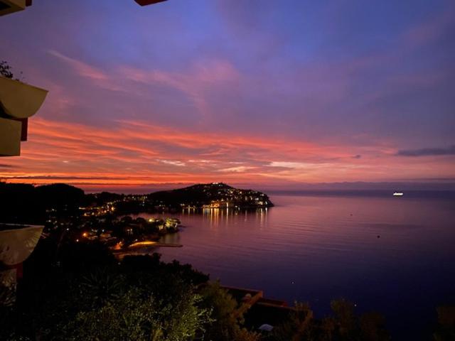 un coucher de soleil sur une étendue d'eau avec une ville dans l'établissement romantica costa azzurra, à Villefranche-sur-Mer