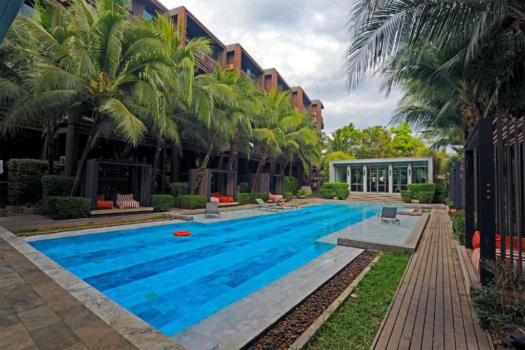 une piscine avec des palmiers et un bâtiment dans l'établissement Saturdays by Holy Cow, à Ban Saiyuan (1)