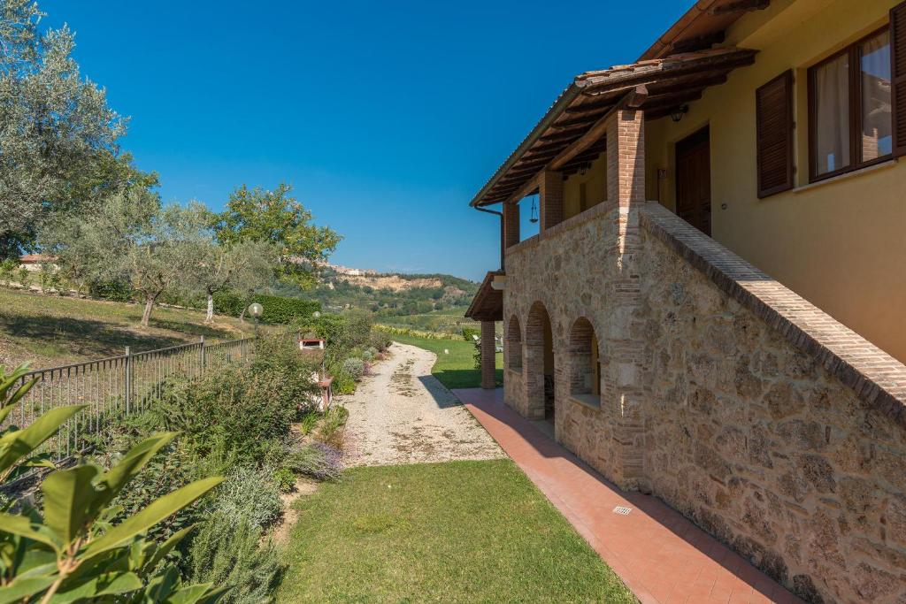 uma casa de pedra com um caminho ao lado de um edifício em The Grapevine by MANVI em Montepulciano