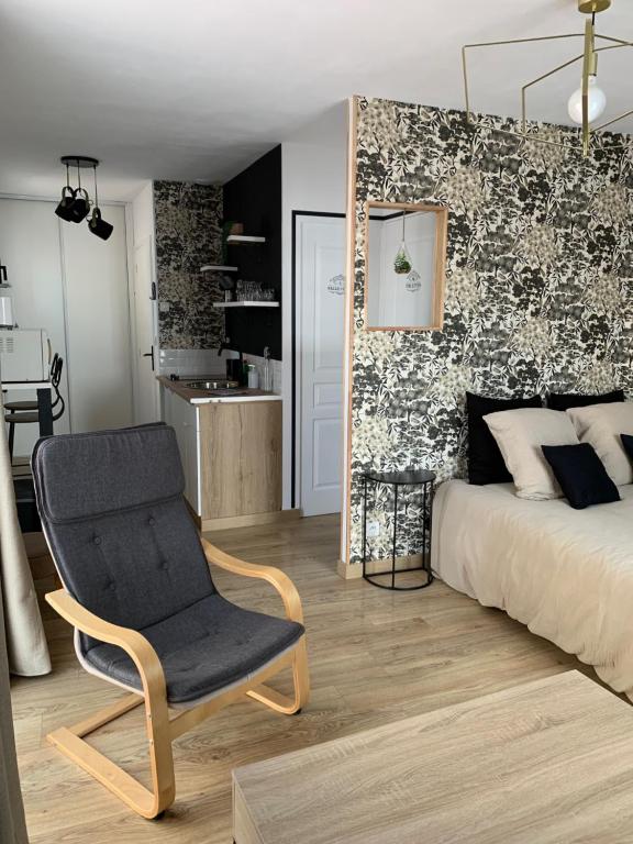 a bedroom with a bed and a chair and a kitchen at Studio Sablé sur Sarthe in Sablé-sur-Sarthe