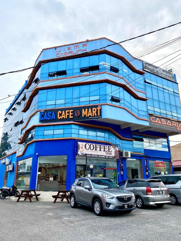 a blue building with cars parked in front of it at Hotel Casaria in Paka