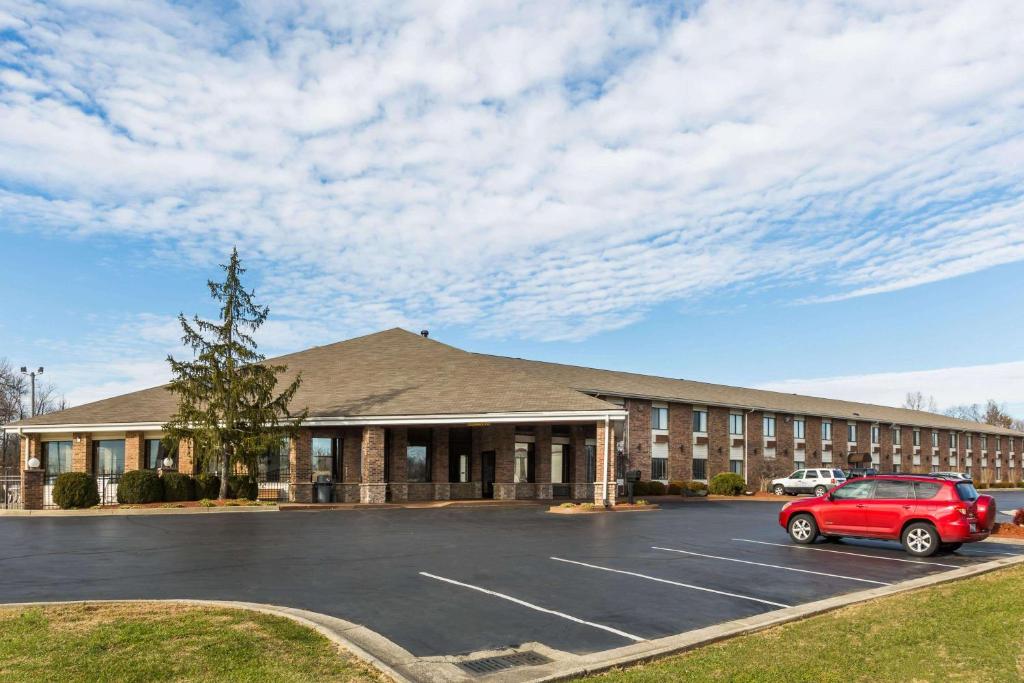 a building with a red car parked in a parking lot at Baymont by Wyndham Louisville South/Shepherdsville/I 65 in Brooks