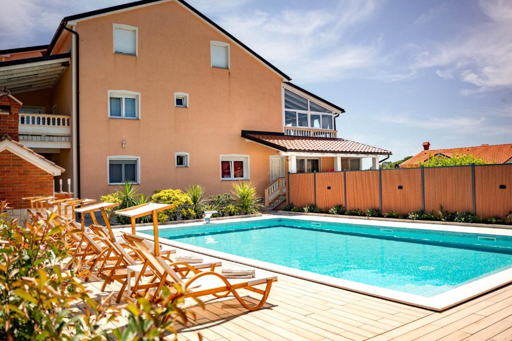 a swimming pool in front of a house at Apartments Foric Rab with Heated Pool, Sauna & Gym in Rab