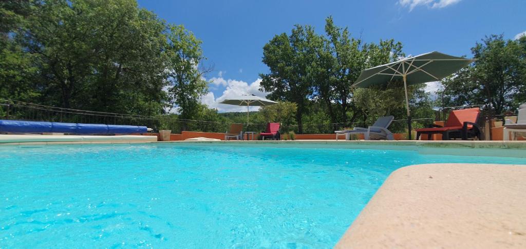 une grande piscine avec chaises et parasols dans l'établissement Maison familiale avec piscine et boulodrome dans le Luberon, à Caseneuve