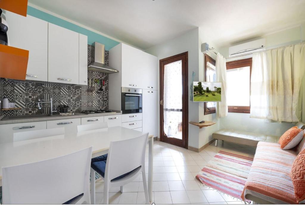 a kitchen with white cabinets and a table and a couch at Casa Vacanze L'Aquilone - casa sulla spiaggia - baia di Porto Rafael in Palau