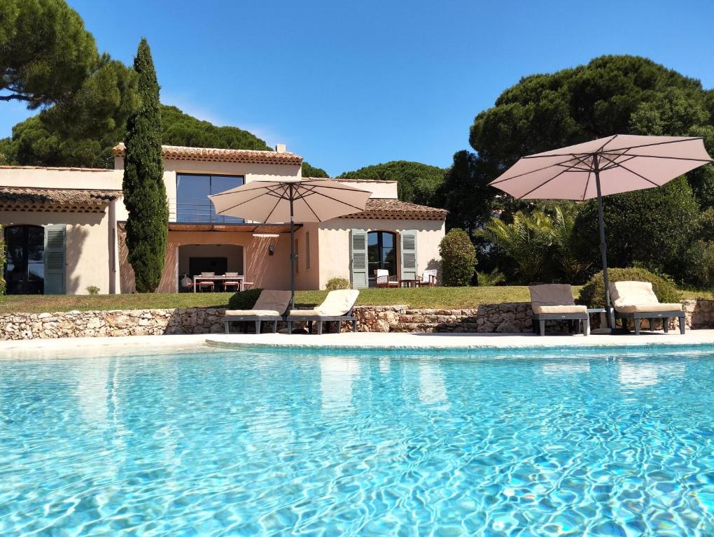 une piscine avec deux parasols et une maison dans l'établissement villacoucourelle saintemaximecom quiet near beach & center with sea and garden views, à La Garonnette-Plage