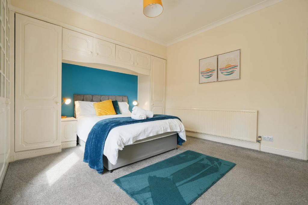 a bedroom with a large bed with a blue headboard at HILLTOP PLACE SUITES 4 Bedrooms near PEAK DISTRICT in Killamarsh