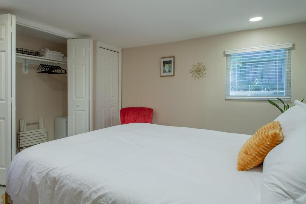 a bedroom with a white bed and a red chair at 2-BR City Retreat Peace Privacy & Parking in Washington, D.C.