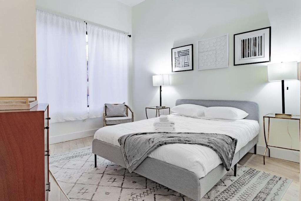 a white bedroom with a bed and a chair at Vibrant 2-BR Luxe Flat Adjacent Eastern Market Walk to METRO Barracks Row Capitol Hill in Washington, D.C.