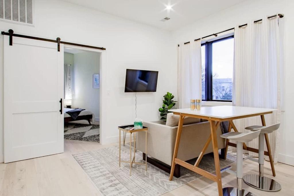 a white living room with a table and a television at Eastern Market & METRO Accessible Modern Charm Walk Everywhere in Washington, D.C.