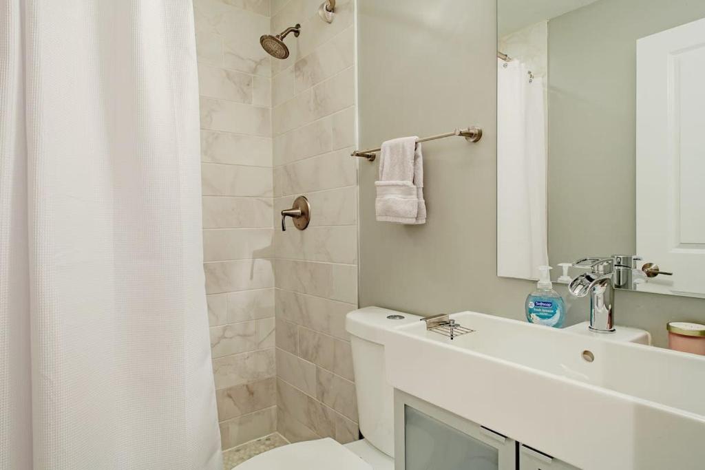 a white bathroom with a shower and a sink at Central DC Flat Sleeps 3 Convention Center in Washington, D.C.