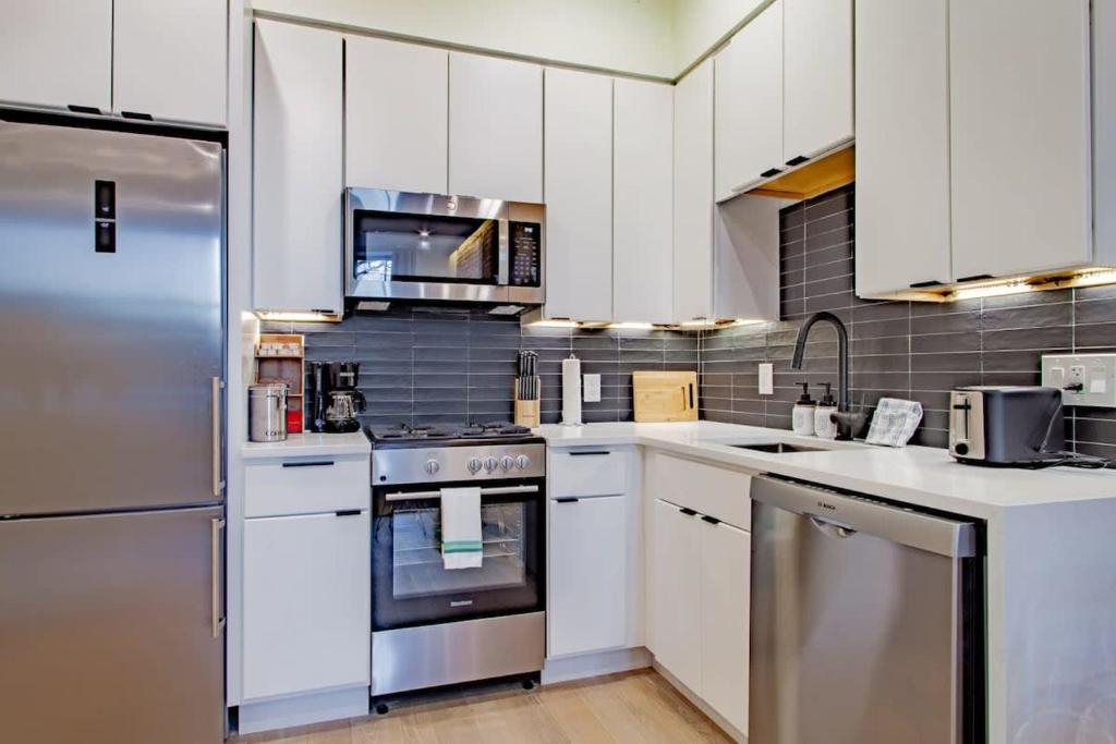 a kitchen with white cabinets and a stainless steel refrigerator at Barracks Row & Eastern Market Oasis Transit-Friendly in Washington, D.C.