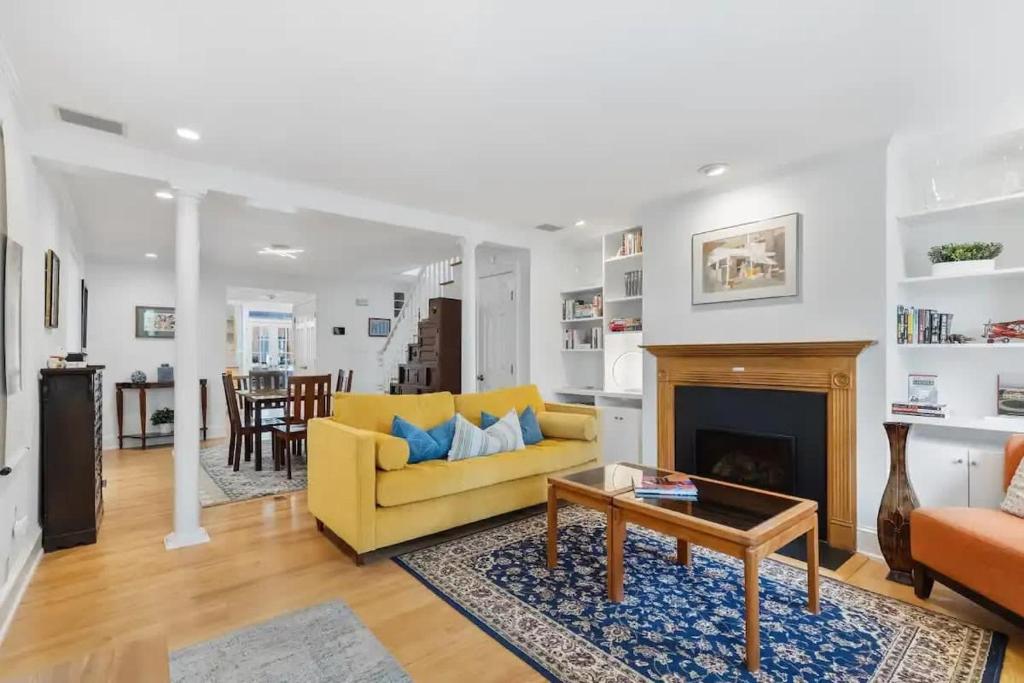 a living room with a yellow couch and a fireplace at Historic & Modern Capitol Hill 2-BR Row Home in Washington, D.C.