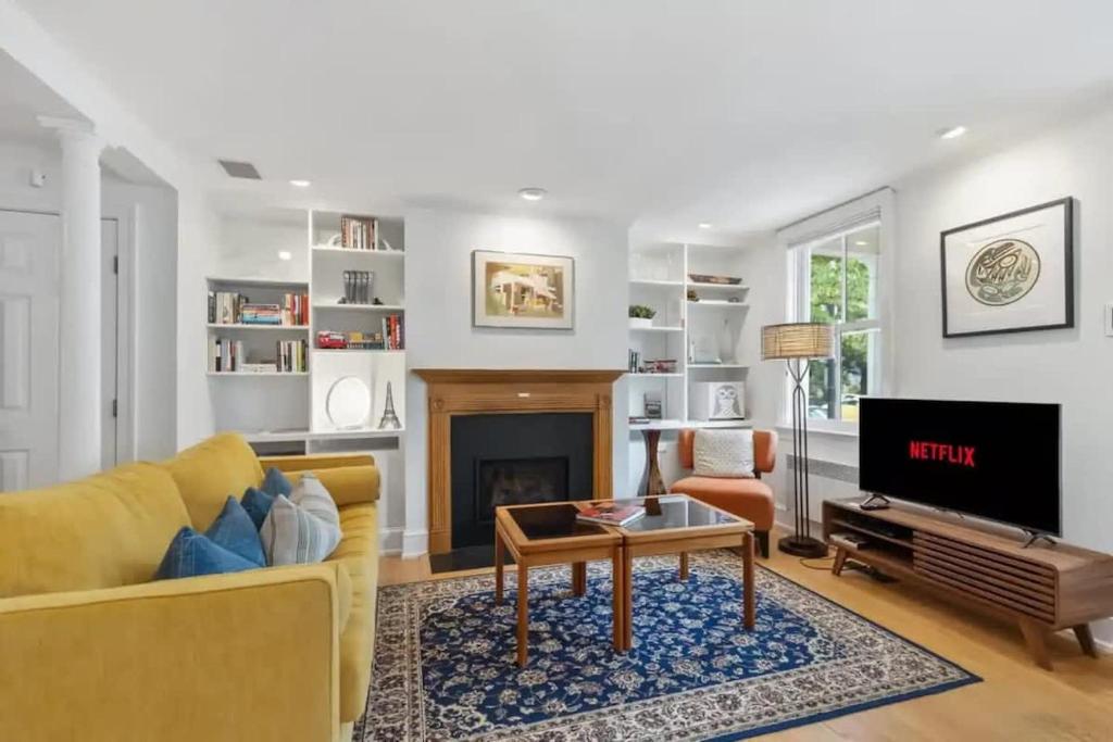 a living room with a yellow couch and a fireplace at Historic & Modern Capitol Hill 2-BR Row Home in Washington, D.C.