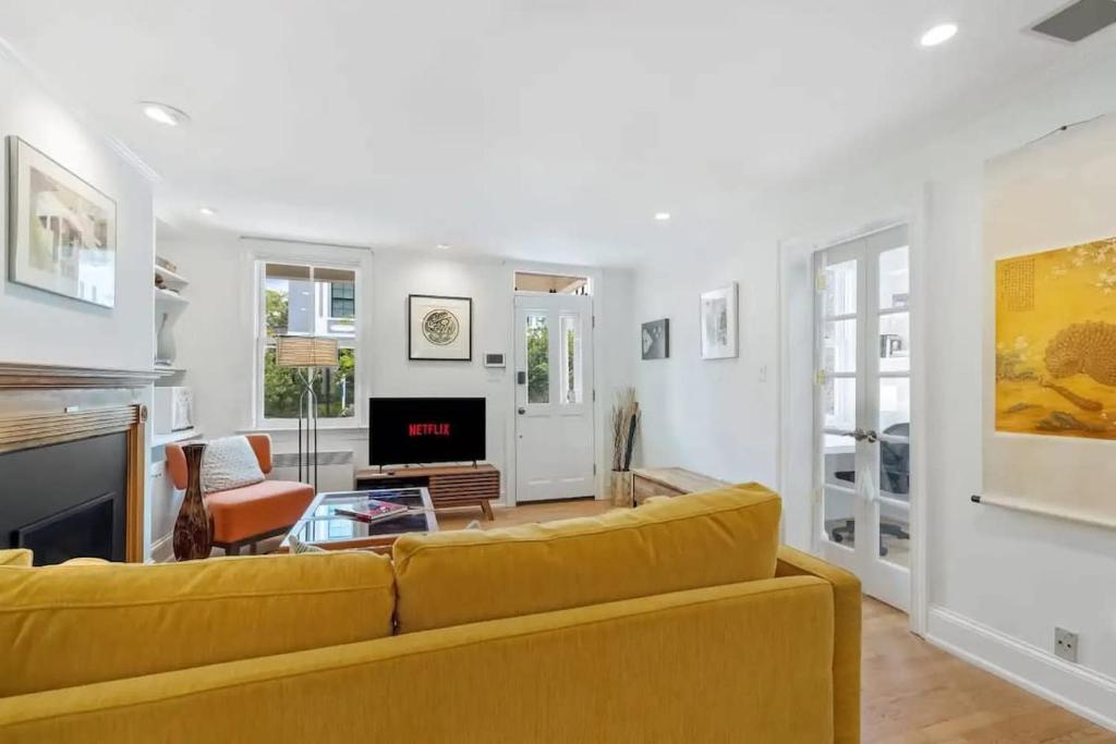 a living room with a yellow couch and a fireplace at Historic & Modern Capitol Hill 2-BR Row Home in Washington, D.C.