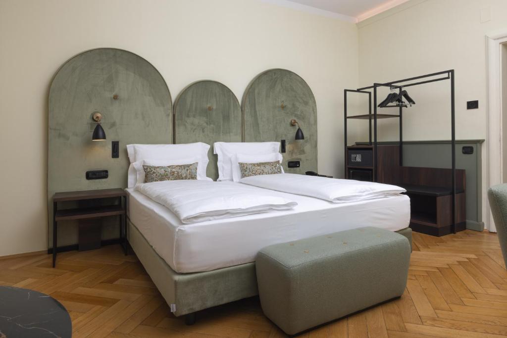 a bedroom with a large bed and a ottoman at Stadt Hotel Citt&agrave; in Bolzano