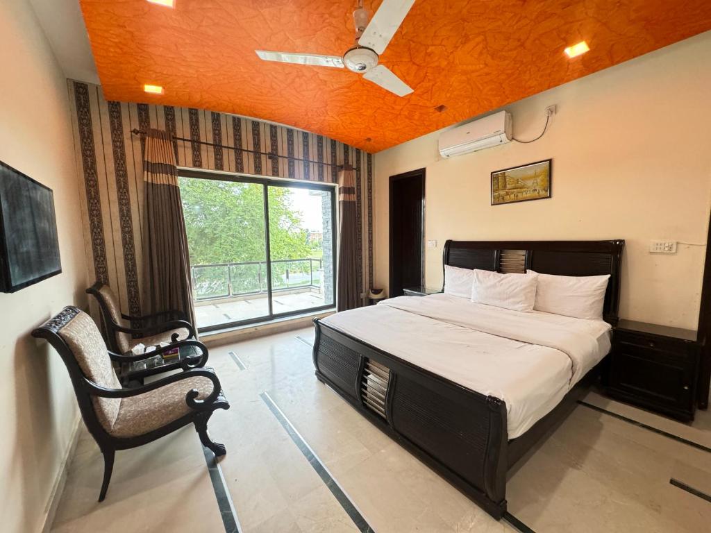 a bedroom with a bed and a chair and a window at Millat Guest House F10-4 in Islamabad