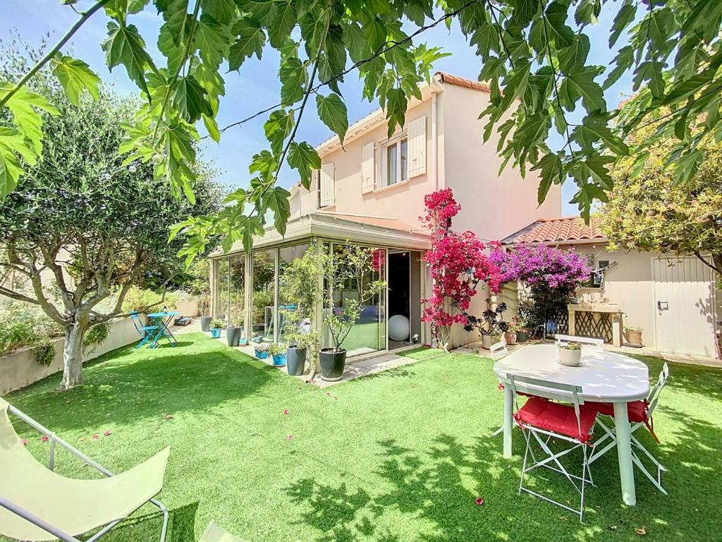 une cour avec une table et des chaises devant une maison dans l'établissement Charmante Villa 4 Pièces avec Piscine, Terrasse et Parking Privé à La Ciotat - Proche Plages - FR-1-770-33, à La Ciotat