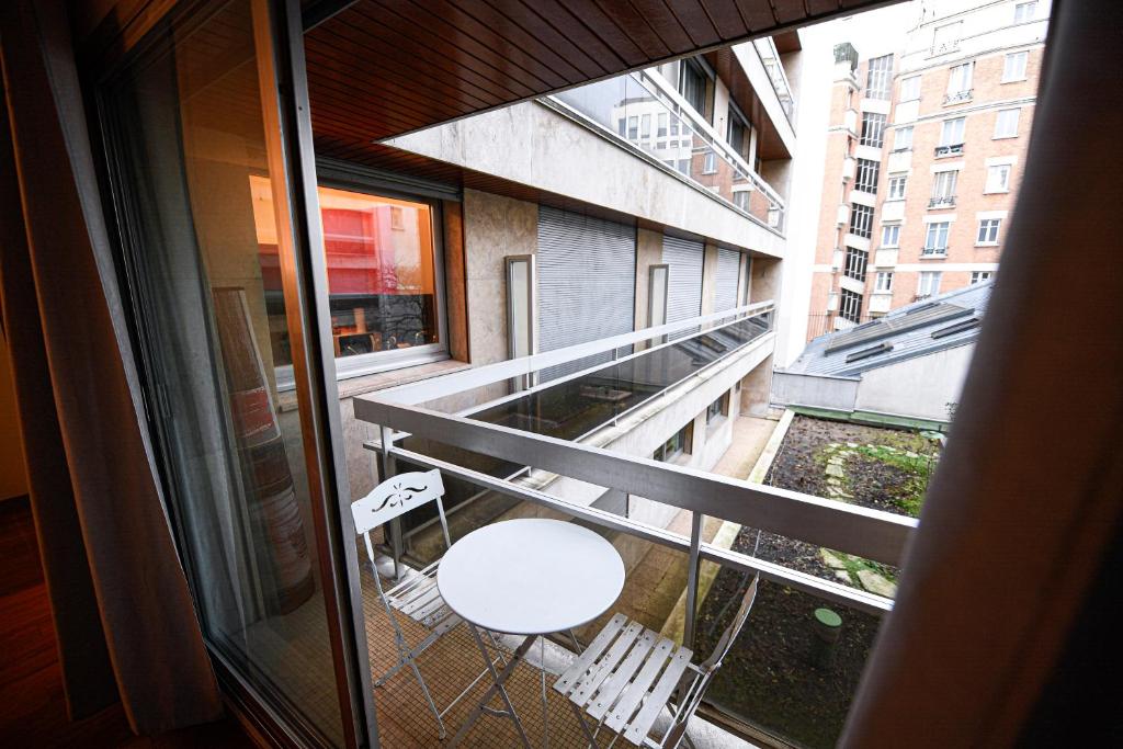 - un balcon avec une table et une chaise blanches dans un bâtiment dans l'établissement Studio de luxe les champs Élysées 2, à Paris