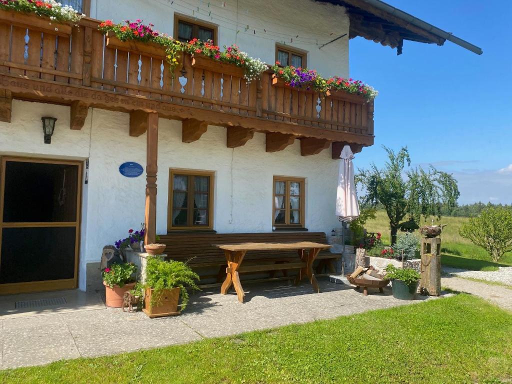 a house with a wooden balcony and a wooden table at Kalbhof in Breitbrunn am Chiemsee