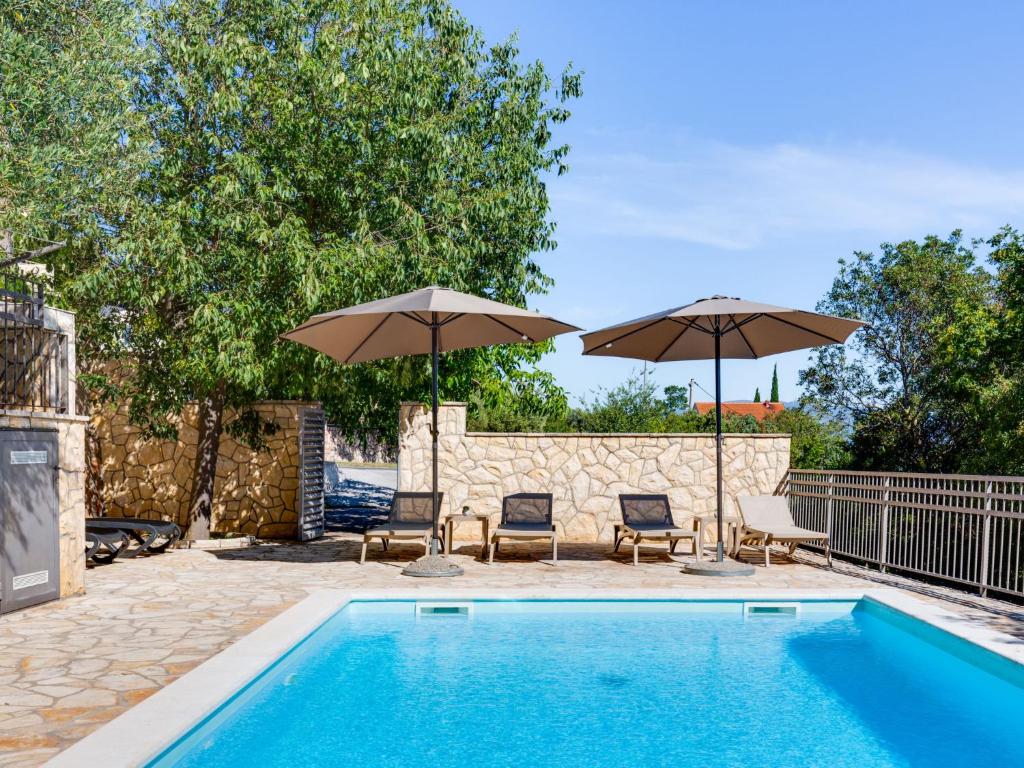 a swimming pool with two umbrellas and two chairs at Apartment Relax-1 by Interhome in Maslenica
