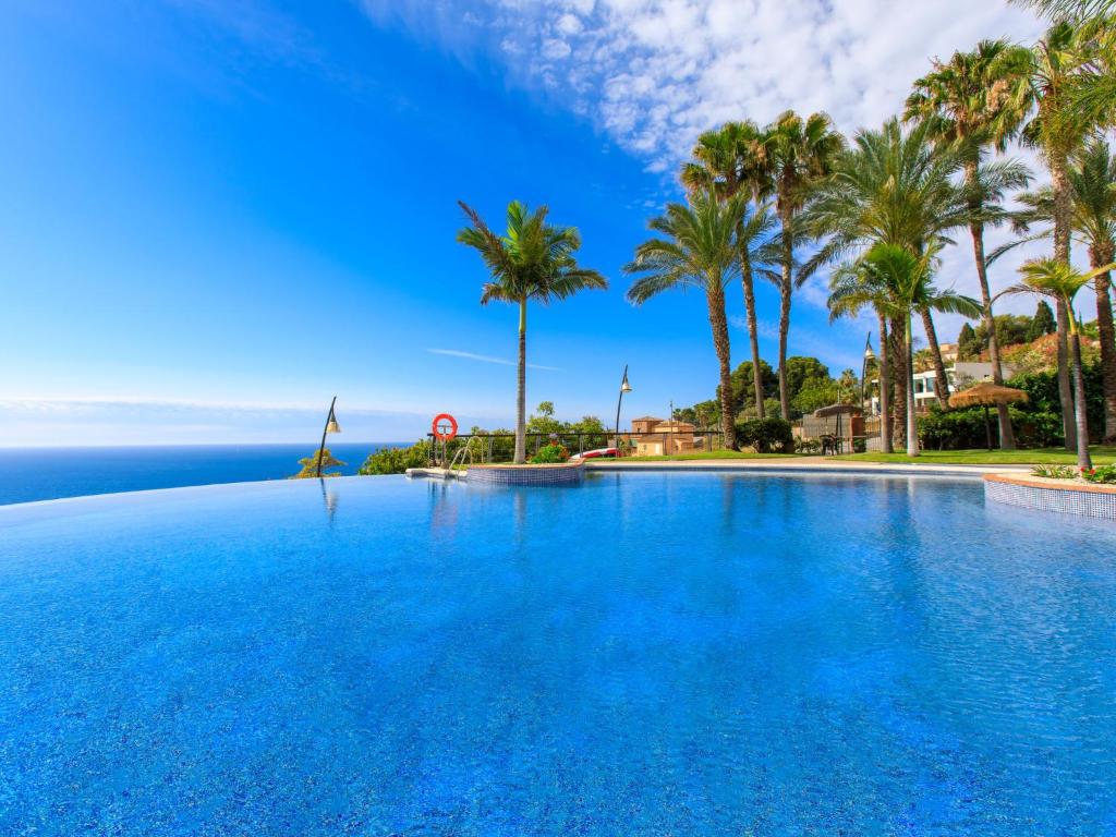 ein großer Swimmingpool mit Palmen und dem Meer in der Unterkunft Apartment Belle Vue by Interhome in Almuñécar