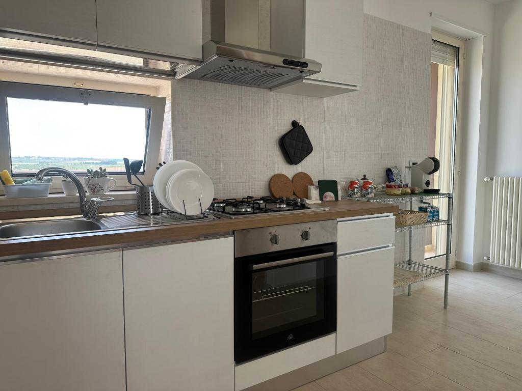 uma cozinha com um lavatório e um fogão forno superior em Attico al Sovrano - Nel cuore della Puglia! em Turi