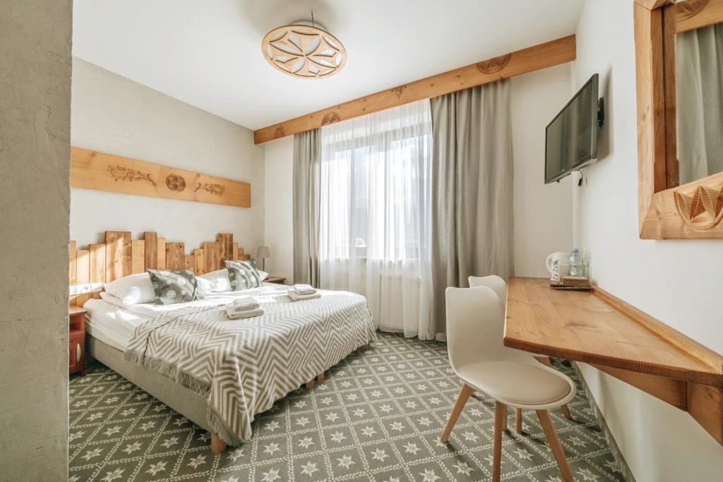 une chambre avec un lit, un bureau et une télévision dans l'établissement Willa Swoboda Garden Spa, à Zakopane