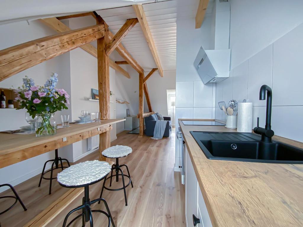 a kitchen with a sink and a counter with stools at Über den Dächern von Kiel in bester Innenstadtlage in Kiel