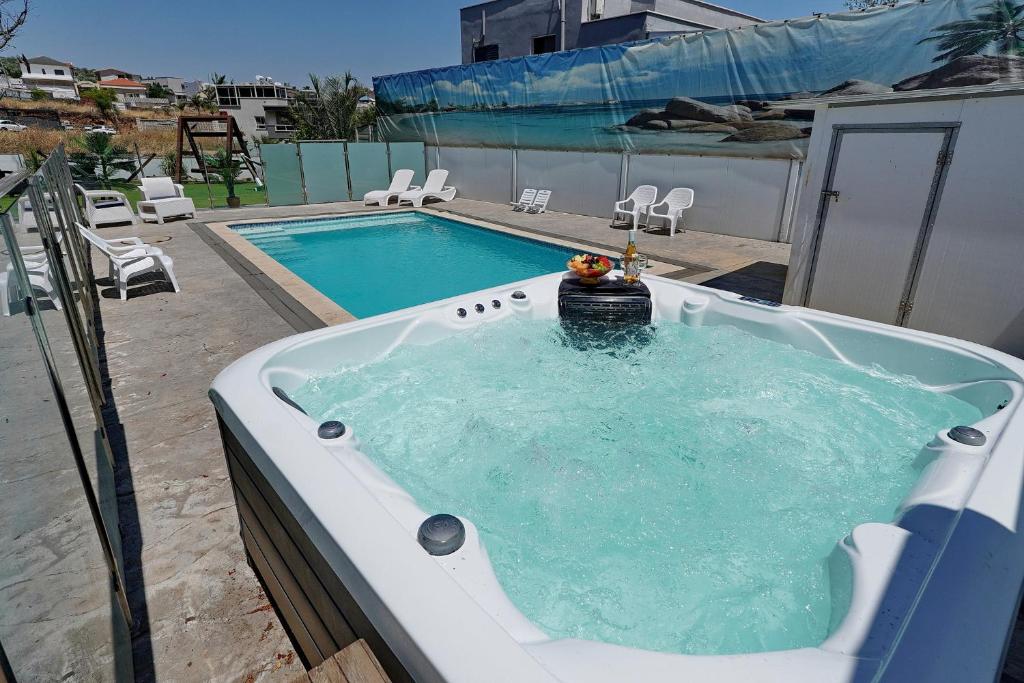 a jacuzzi tub with a pool in a backyard at שלווה במושבה מגדל - וילה מדהימה עם בריכה פרטית וג'קוזי ליד הכנרת in Migdal