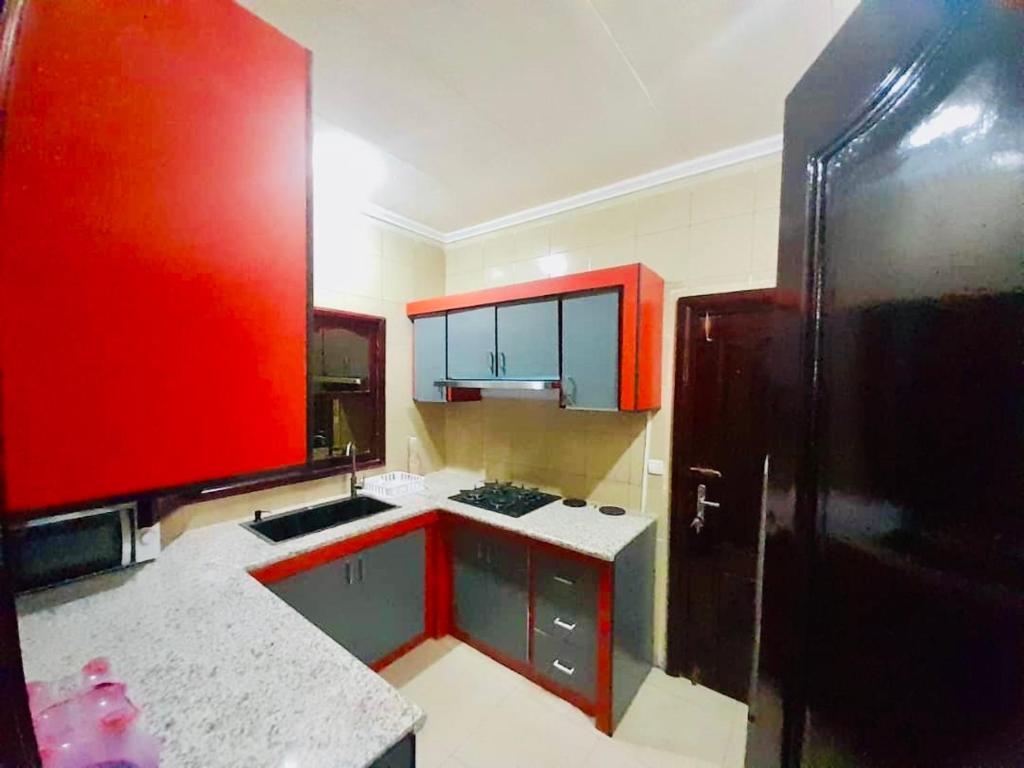 a kitchen with red cabinets and a black refrigerator at Chez soi loin de chez soi in Pointe-Noire