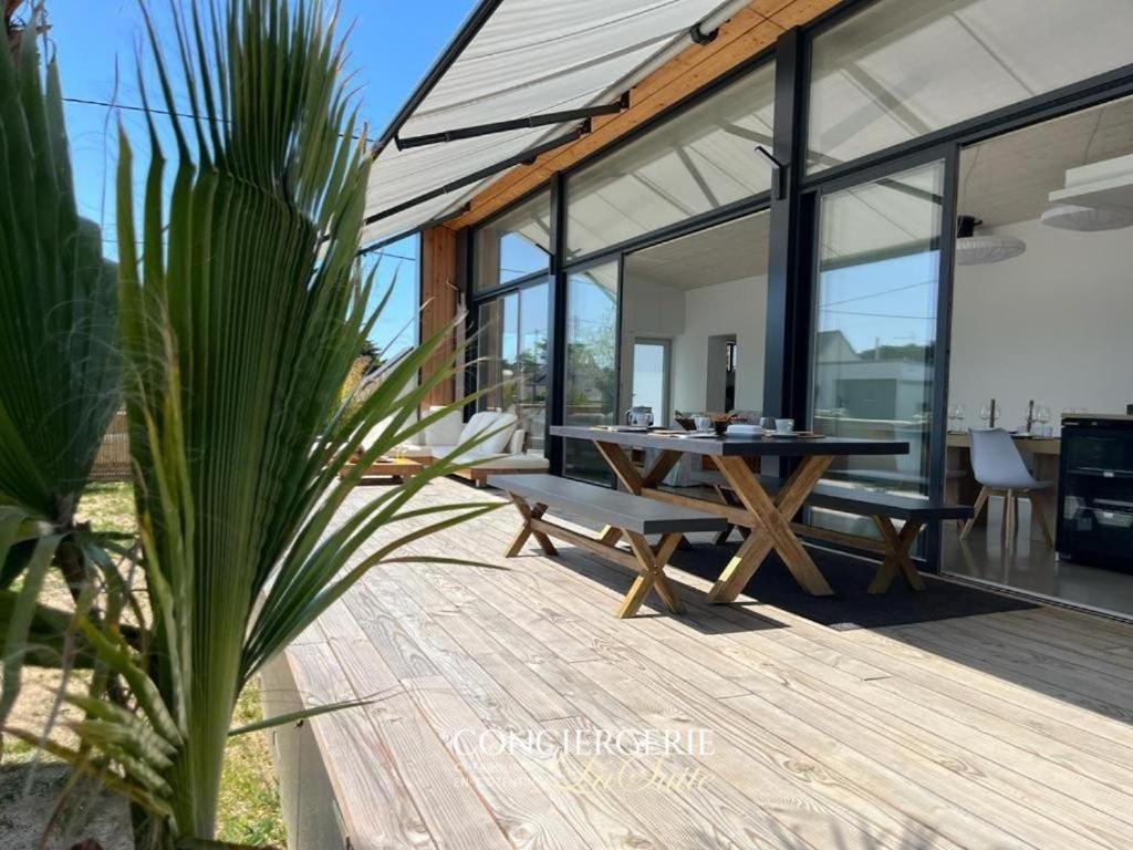 une terrasse en bois avec une table et des bancs sur une maison dans l'établissement La fauvette, à Barneville-Carteret