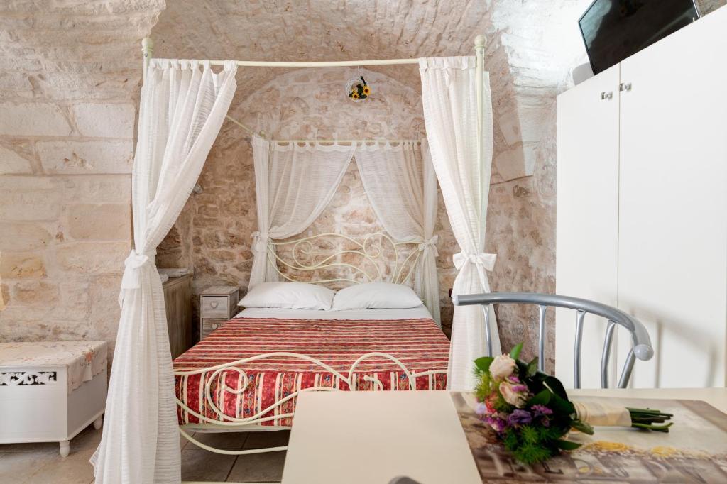 Un dormitorio con una cama con dosel y cortinas blancas. en Profumo di Pietra, en Martina Franca