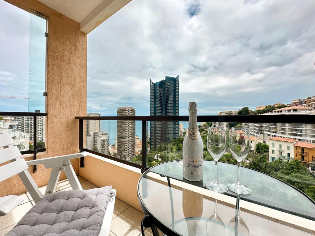 - une table en verre avec 2 verres à vin sur le balcon dans l'établissement Luxurious 3 Rooms, Pool, Bnbrickeys, à Beausoleil