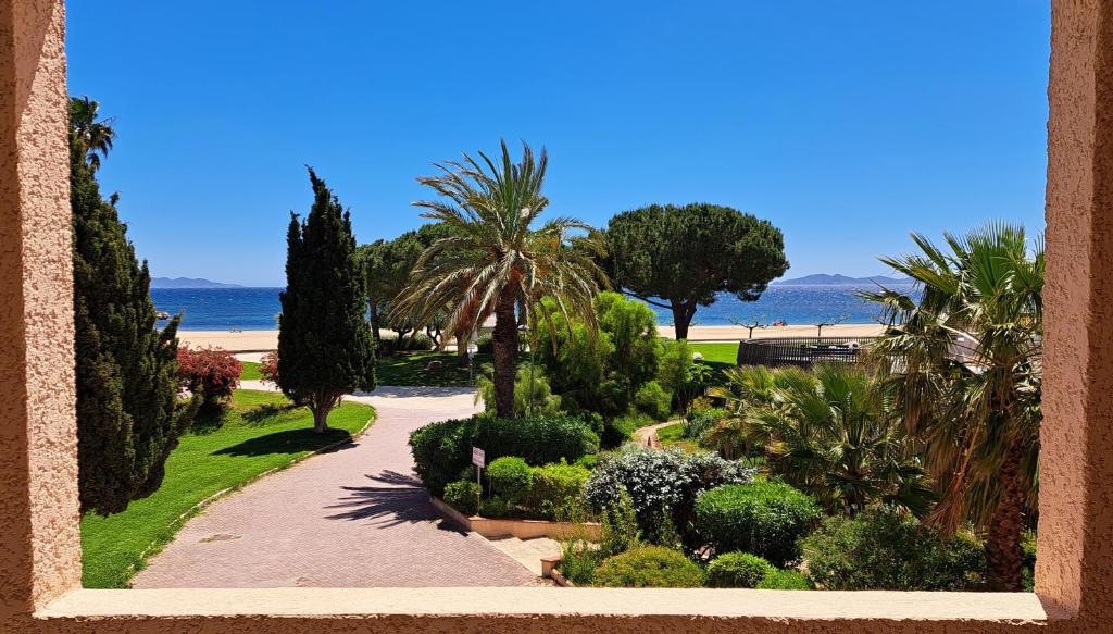 Elle offre une vue sur un jardin planté d'arbres et de buissons. dans l'établissement Appartement face à la mer avec parking, à La Londe-les-Maures