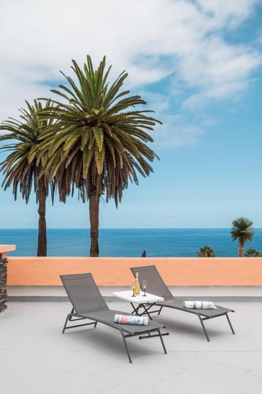 two chairs and a table on a beach with palm trees at Mar Celeste in Puerto de la Cruz