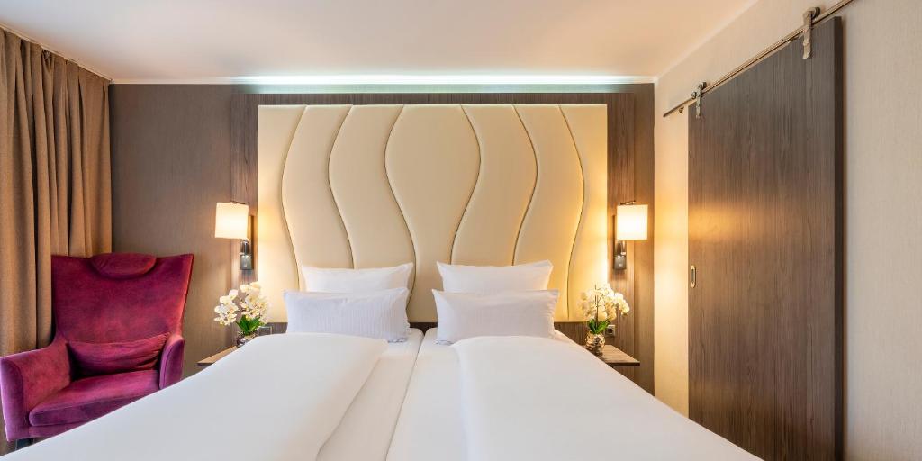 a bedroom with a large white bed and a purple chair at PLAZA Residence Stuttgart-Ditzingen in Ditzingen