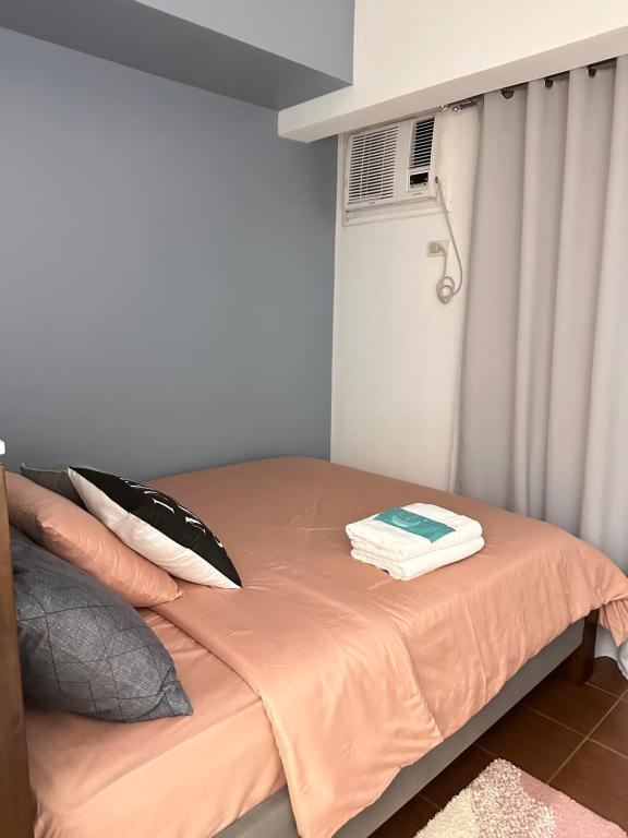 a bed with a orange blanket and pillows in a room at 1BR Cozy Condo at Kasara Urban Resort Pasig City in Manila