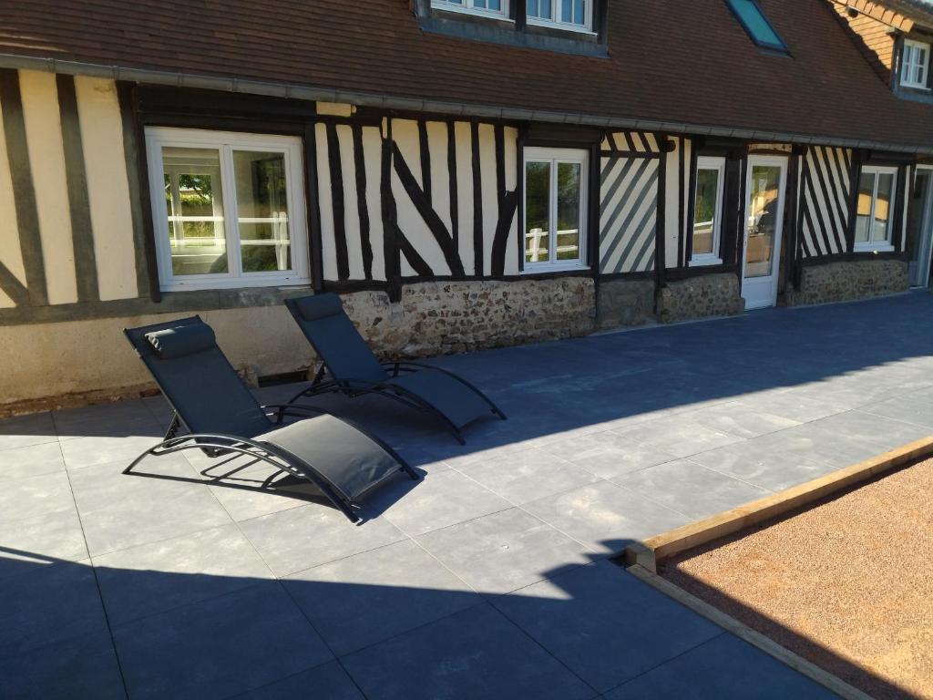 2 chaises assises sur une terrasse en face d'un bâtiment dans l'établissement Gite Le dorm'eure du Val - SPA, à Saint-Pierre-du-Val