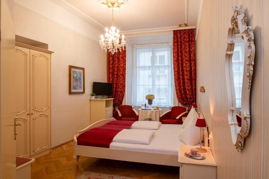 um quarto com uma cama com um cobertor vermelho em Pertschy Palais Hotel em Viena