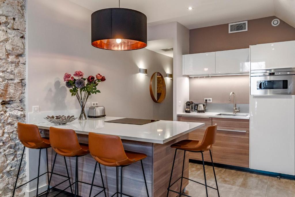 een keuken met een groot wit eiland met oranje stoelen bij Luxury Family 2BR - Prime Location, Walk to Beach & Shopping, Sunny Balcony - By Totolulu Cannes Hoche in Cannes