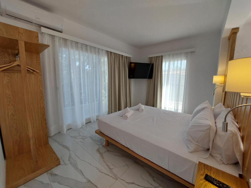 a bedroom with a large white bed and windows at Blue Bay Hotel in Iraklitsa