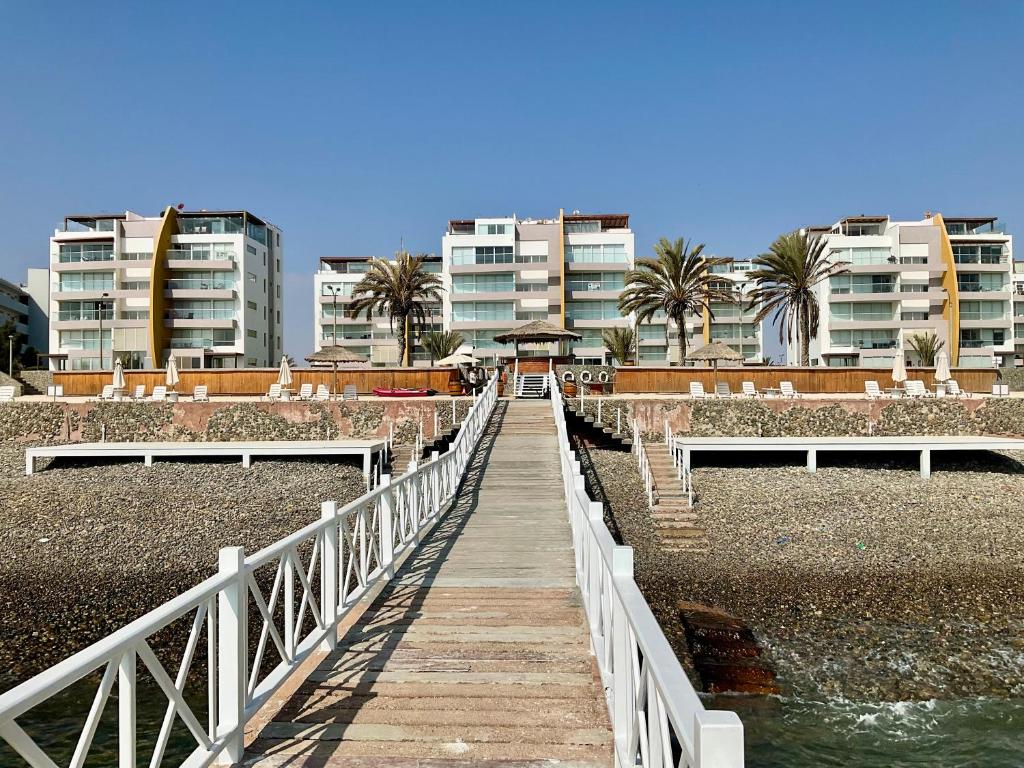 una passerella di legno che conduce a una spiaggia con edifici di 1er Piso Vista a Bahía Paracas - Las Velas 102 T1 a Paracas