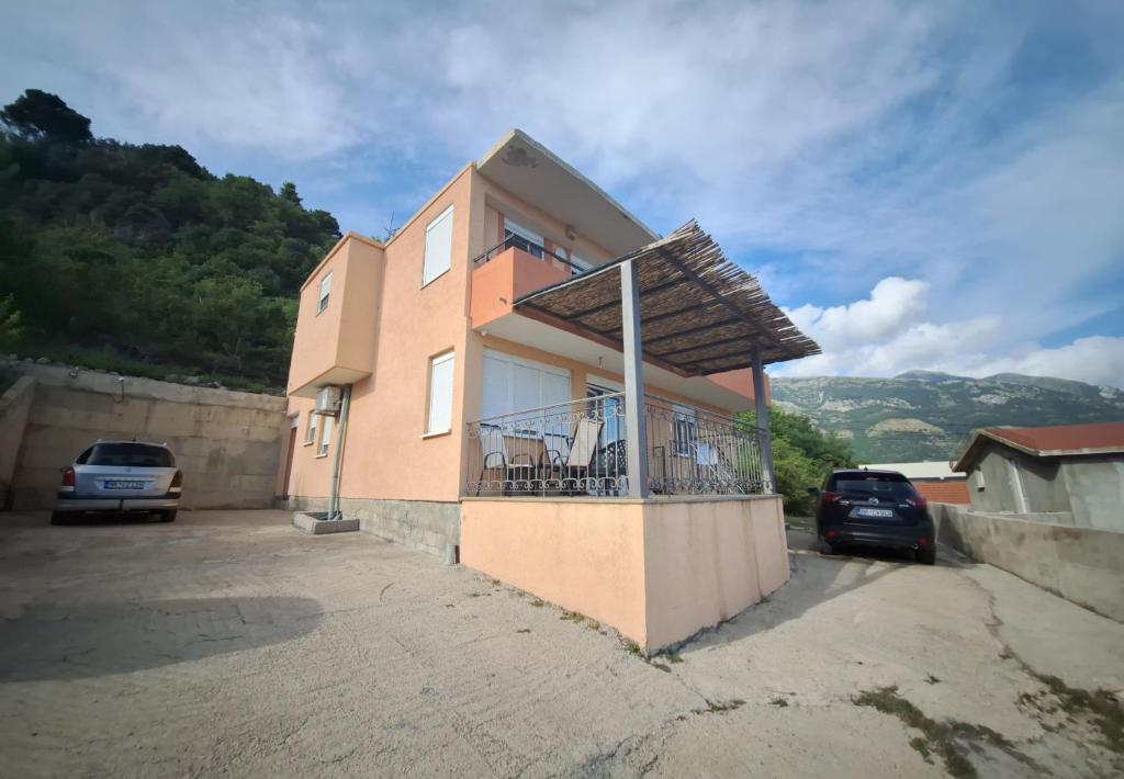 a building with a balcony with cars parked in front of it at Apartmani Seaview in Sutomore