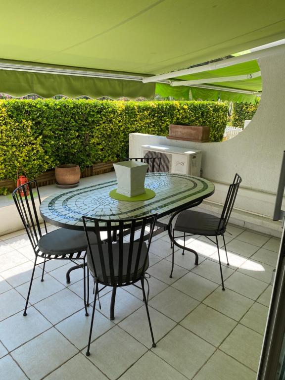 un patio avec une table et des chaises sur un patio dans l'établissement Appartement 4 personnes avec terrasse et piscine proche plage et commerces, à La Grande Motte