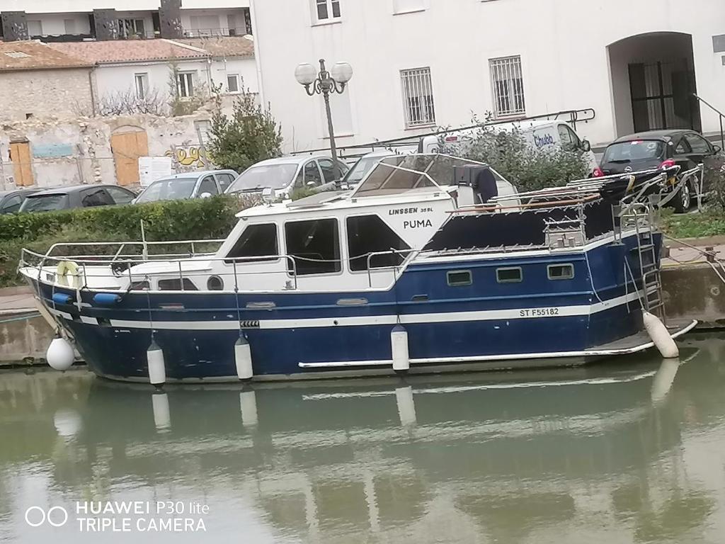un bateau bleu et blanc assis dans l'eau dans l'établissement Appartement bateau Narbonne, à Narbonne