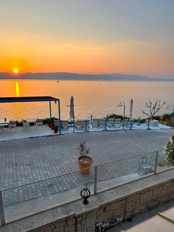 a sunset over a body of water with tables and chairs at Fener Hotel Café & Kahvalti in Çeşme